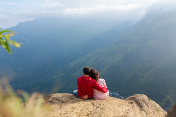 Fototapeta premium A guy with a girl cuddling with a beautiful view of the mountains. Romance in a picturesque place