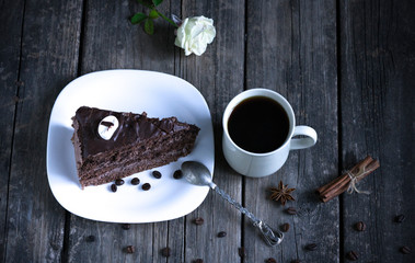 a piece of cake in a plate and a cup of coffee on a wooden background