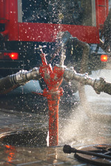 Water splashes from the fire hose and hydrant connections. Firefighters Work Concept