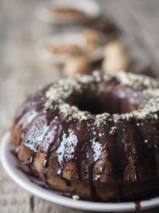 Festive homemade cakes. Round chocolate muffin, large muffin or chocolate icing cake on a wooden ancient background with nuts, raisins, and cinnamon. Place for text.