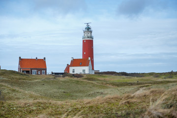 Fototapeta na wymiar red lighthouse on an island with dunes