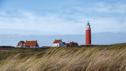 Fototapeta na wymiar red lighthouse on an island with dunes