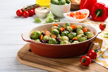 Roasted Brussels sprouts with beans and carrot in baking dish on white wooden table