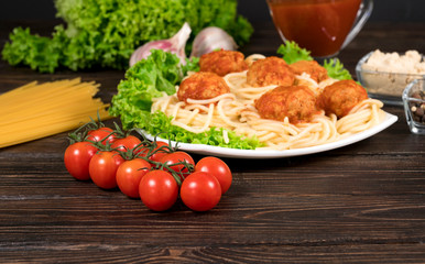 Meat balls in tomato sauce Tagliatelle and basil on a wooden background