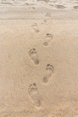 Fototapeta na wymiar Deep bare footprints with fingers on the sand at the beach