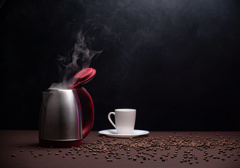Electric kettle and coffee beans on dark background