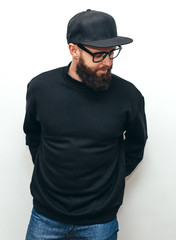 Portrait of handsome hipster guy with beard wearing black blank hoody or sweatshirt and black cap...