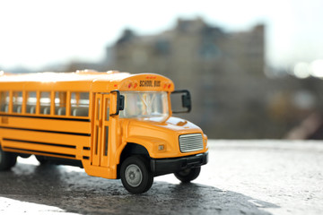 Yellow toy school bus on road outdoors. Student's transport