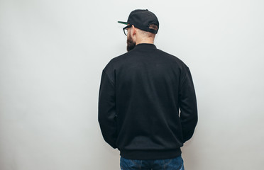 Portrait of handsome hipster guy with beard wearing black blank hoody or sweatshirt and black cap...