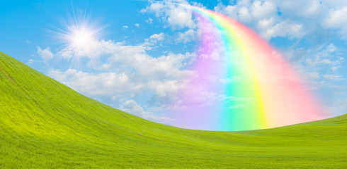 Fototapeta na wymiar Green grass field with rainbow and sun