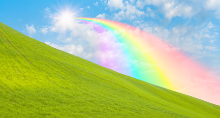 Obraz na płótnie Canvas Green grass field with rainbow and sun