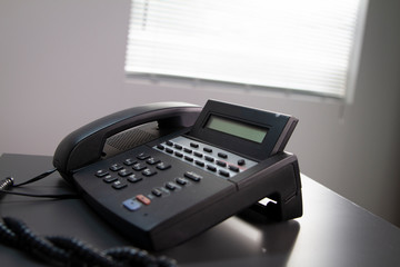 Black Office Telephone on a Grey Desk