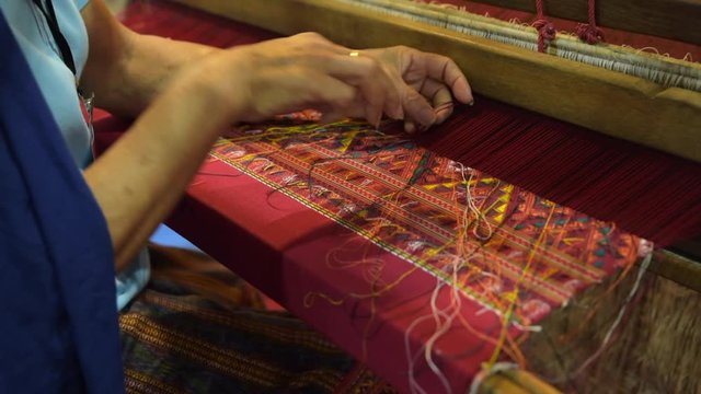 Traditional Thai silk weaving. old woman hand-weaving silk in a traditional way at the manual loom, in Thailand.