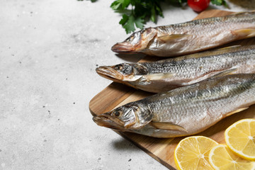 Smoked or dried smelt fish on a wooden Board on a gray kitchen table. Space for text