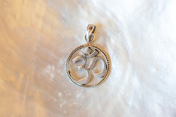 Sterling silver pendant with mandala om symbol on white mother pearl background
