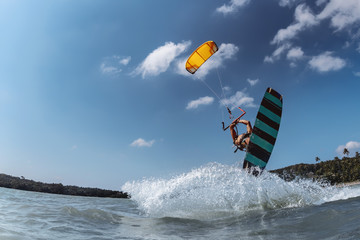 Kite surfer jumps against blue sky