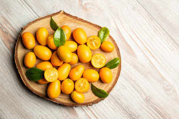 Pile of kumquat fruits, chinese tangerines, on wooden cutting board.
