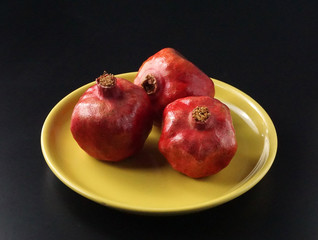 Red pomegranates on a yellow plate