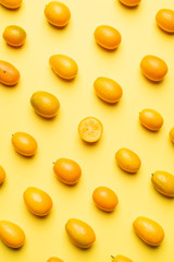 Kumquat fruits in rows on yellow background.