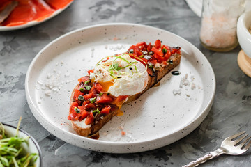 Sandwich with red fish, poached egg, balsamic vinegar and micro-greens