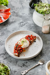 Sandwich with red fish, poached egg, balsamic vinegar and micro-greens