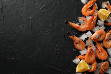 Shrimps, lemon and ice on black background, top view