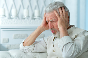 Senior man with headache holding hands on forehead