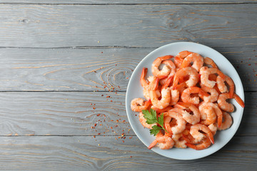 Plate with shrimps on wooden background, top view