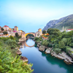 Fototapeta na wymiar Majestic evening view of Mostar with the Mostar Bridge, houses and minarets, at evening