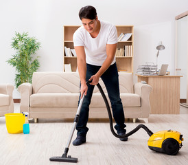 Fototapeta na wymiar Man cleaning home with vacuum cleaner