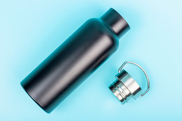 A black reusable bottle for water on blue background, top view