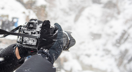 Photographer hands holding camera with snow in winter season. - Powered by Adobe