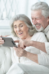 Portrait of happy senior couple using tablet at home