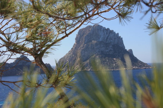 The island of Es Vedra between the blue sky and the blue sea of ​​the Ibizan coasts in front of the Cala D'Hort beach in the Balearic Islands