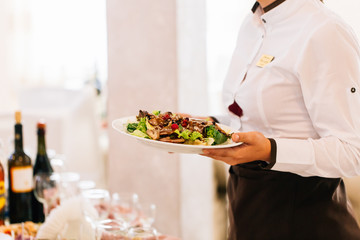 Waiter holding plate with salad in restaurant