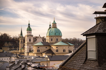 Fototapeta na wymiar Impressive evening scenery over Salzburg: Rooftops of Cathedral, churches and houses