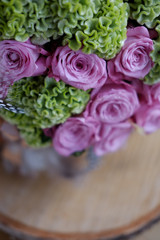 Beautiful spring bouquet close-up with pink roses and green carnations, decorated with feathers and birch bark. 
