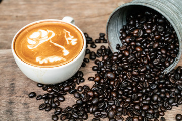 Latte art coffee cup with coffee bean on wood table