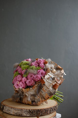 Beautiful spring bouquet close-up with pink roses and green carnations, decorated with feathers and...