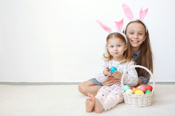 Obraz na płótnie Canvas Two little cute girls with easter basket on a light background. Happy easter! Easter background.