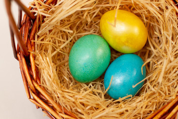 multicolored easter eggs in a brown basket of twigs