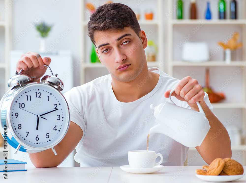 Wall mural man with alarm clock falling asleep at breakfast