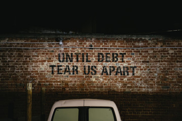 Until Debt Tear Us Apart stencilled in a car park