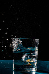 Multicolored splashes of summer. Fresh fruit and splashes of water.The photo shows a slice of green apple thrown into a glass of water. Splashes of cool drink refresh.
