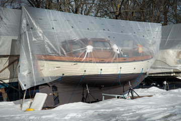 Obraz na płótnie Canvas covered wooden boat on land in winter