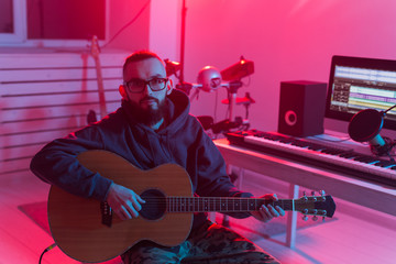 Obraz premium Create music and a recording studio concept - Bearded man guitarist recording electric guitar track in home studio