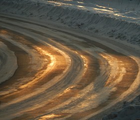 a sharp turn of a snowy road in the golden glare of the morning sun