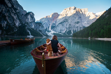 women in a boat on a mountain lake. Traveling with a pet to Italy. girl with Dog