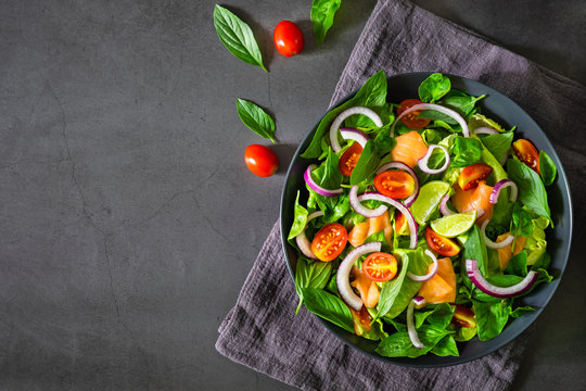 Salmon Salad, View From Above Fresh Tomato, Onion, Spinach, Lettuce , Basil In Black Bowl On Napkin With Dark Backgrond. Healthy Food, Home Made Concept. Tasty And Meal. Top View, Copy Space.