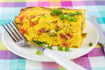 Breakfast casserole with bacon, potatoes, vegetables.